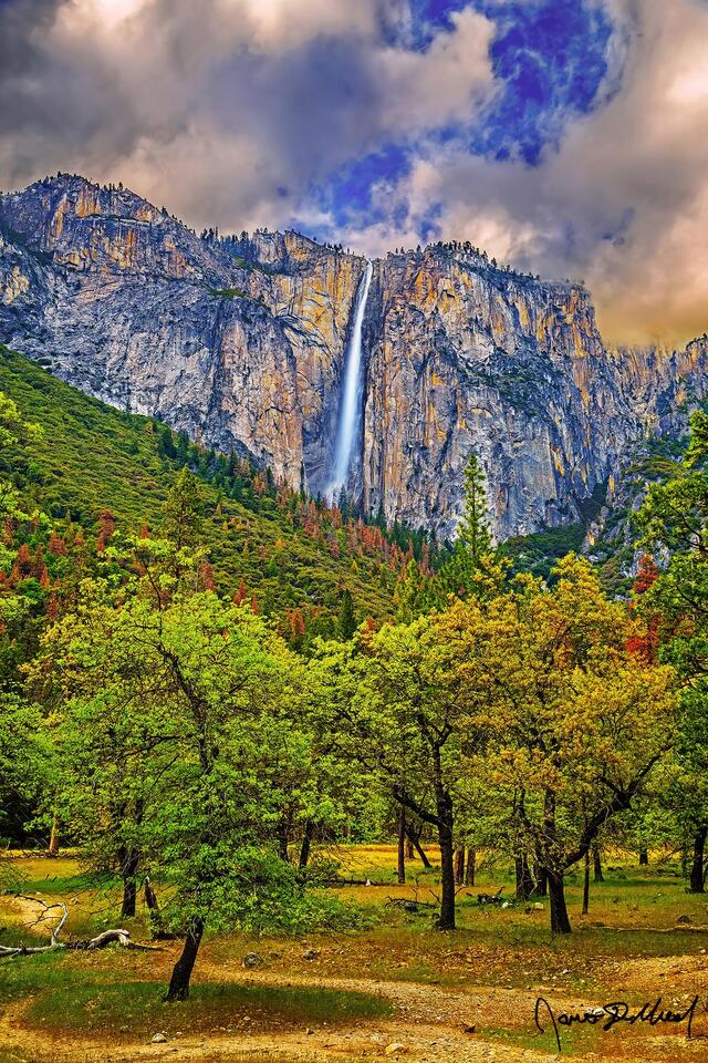 Ribbon Fall drops 1,612 foot drop into Yosemite Valley and Bridalveil Meadow in the spring at sunset, as storm clouds line the skies above.