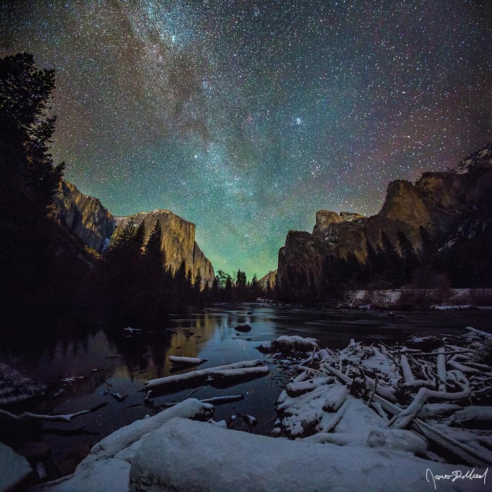 The Winter Milky Way rises up from between the El Capitan and Cathedral Rocks as the Merced River flows through the snow-covered meadows of Yosemite Valley.