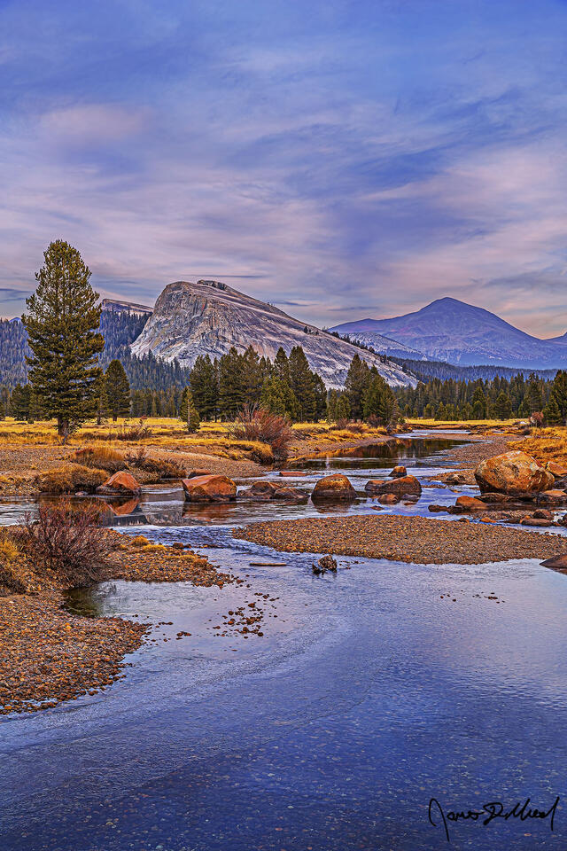 The Tuolumne River begins to freeze over for the winter in Tuolumne Meadows, as faint colors of sunset illuminate the clouds above Lembert Dome and Mount Dana