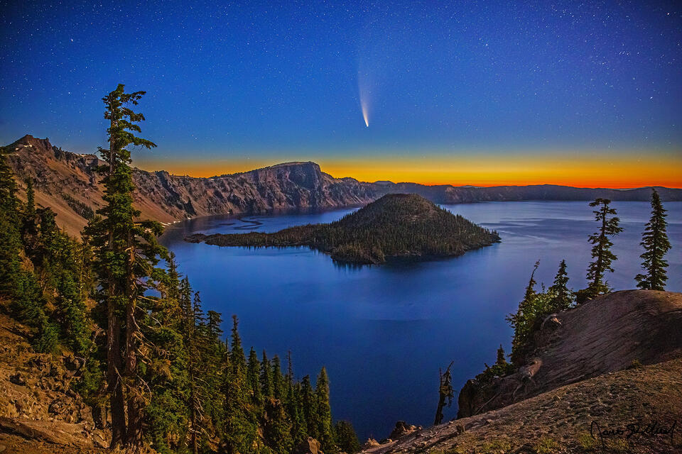 The moon illuminates Crater Lake, the caldera rim and Wizard Island as Comet NEOWISE shines in sky. The last bit of night fades away as Nautical Dawn set in.