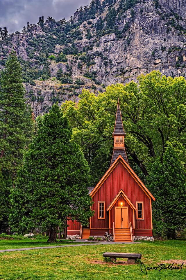 Yosemite Valley Chapel stands at the edge of Cook’s Meadow in the spring, as the granite cliff rise 3000 feet above the Yosemite Valley floor.