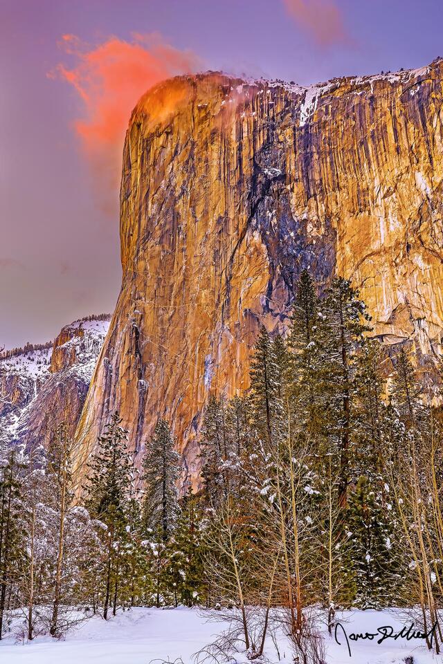 Sunset lights color across the skies above El Capitan and Yosemite Valley as a lone cloud on it's tip lights orange like fire.