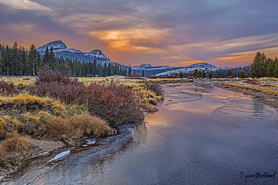 Ice forms on the Tuolumne River as it begins to freeze over for the upcoming winter. Sunset lights the skies above Fairview Dome, Daff Dome and Pothole Dome
