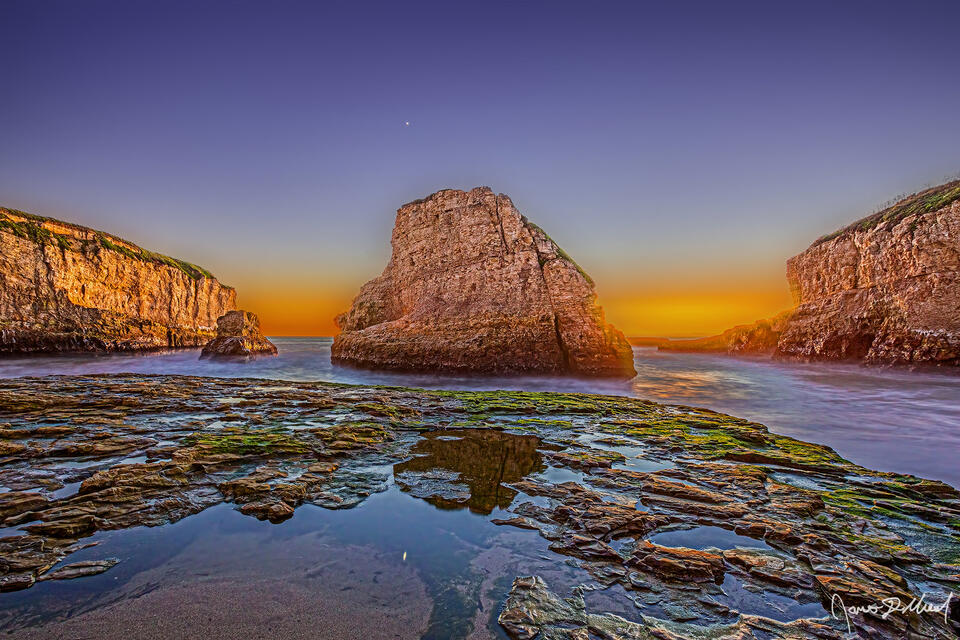 Dusk sets in over the Pacific Ocean as Venus reflects in the tide pools of Shark Fin Cove along the Pacific Coast Highway in California