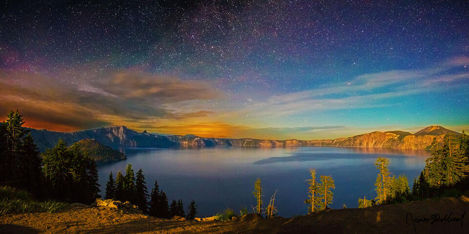 The Milky Way spiral arm rises above Crater Lake and strong aurora induced airglow as moonlight illuminates the lake, Wizard Island and the caldera rim.