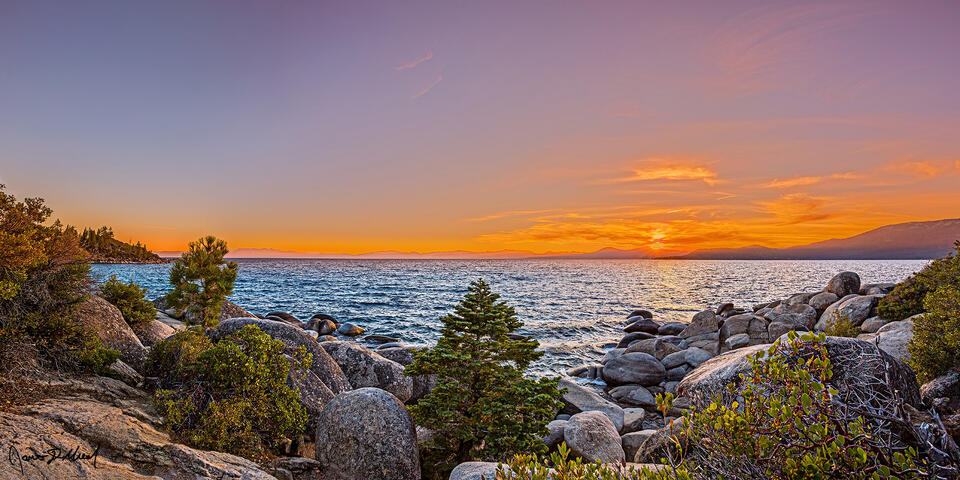 Sunset lights the skies over Lake Tahoe and granite boulders at Memorial Point as the sun creates a Sunstar off the Sierra Nevada peaks lining the horizon