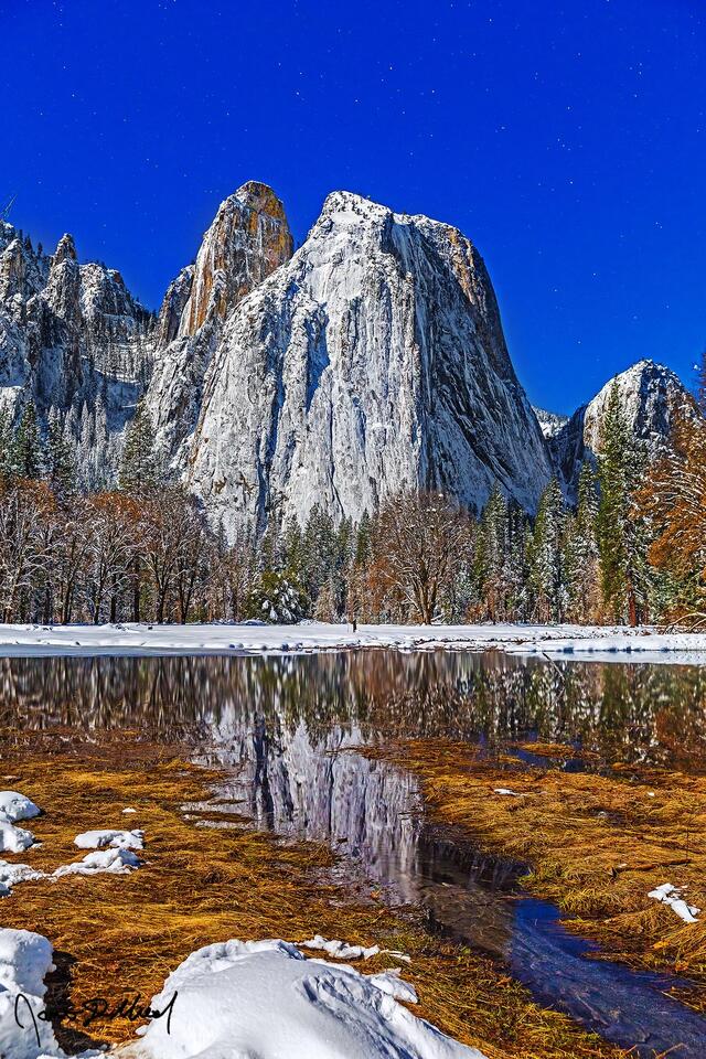 Moonlight illuminates Yosemite Valley as it lay covered in a blanket of deep snow. Cathedral Rocks and Spires reflect in the still waters of Wosky Pond 