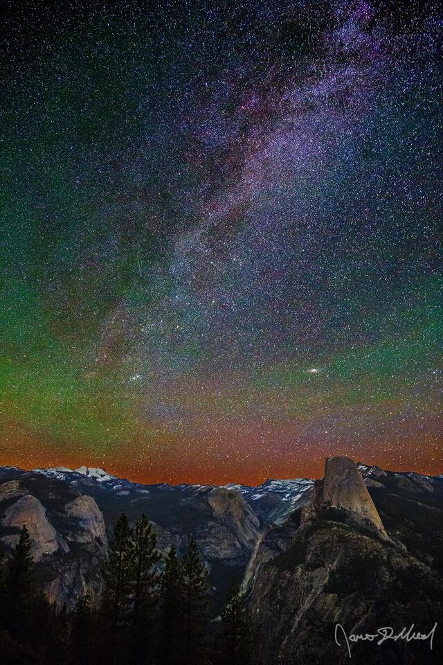The Milky Way spiral arm and the Andromeda Galaxy rise into the sky above Half Dome, Quarter Domes, Basket Dome, North Dome, Mount Watkins and Cloud's Rest.