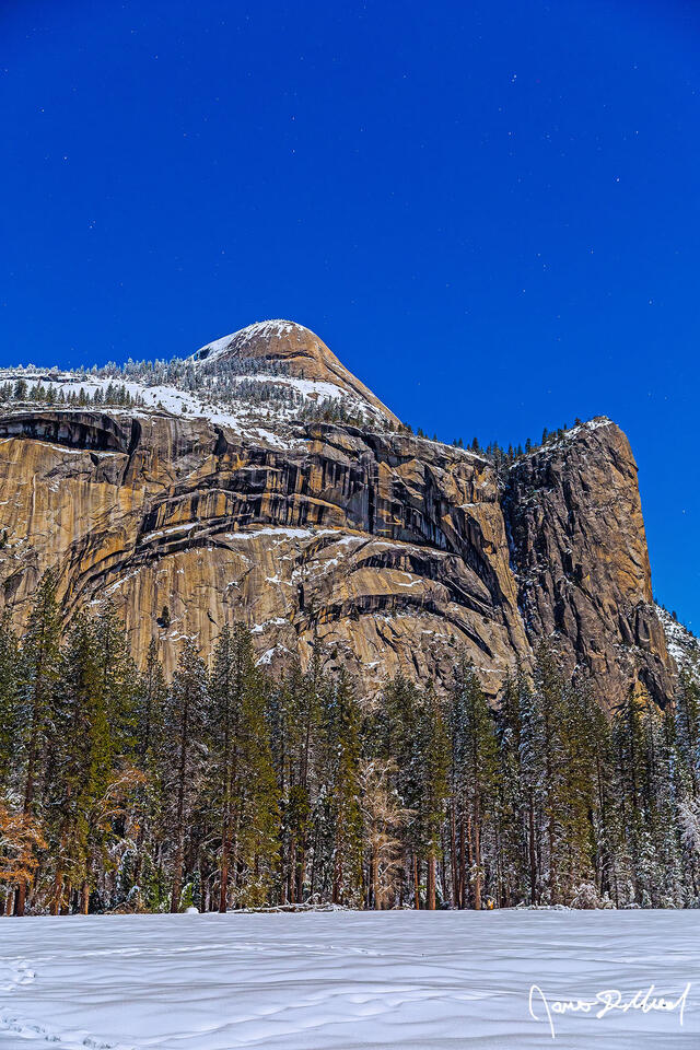 Moonlight illuminates North Dome, Royal Arches, Washington Column and snow covered Stoneman Meadow as Yosemite Valley transforms into a winter wonderland.