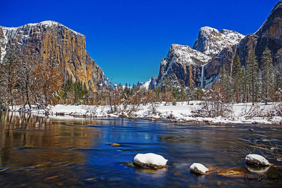 Moonlight illuminates Yosemite Valley, El Capitan, Cathedral Rocks, Bridalveil Fall and the Merced River in the winter as snow blankets the ground.