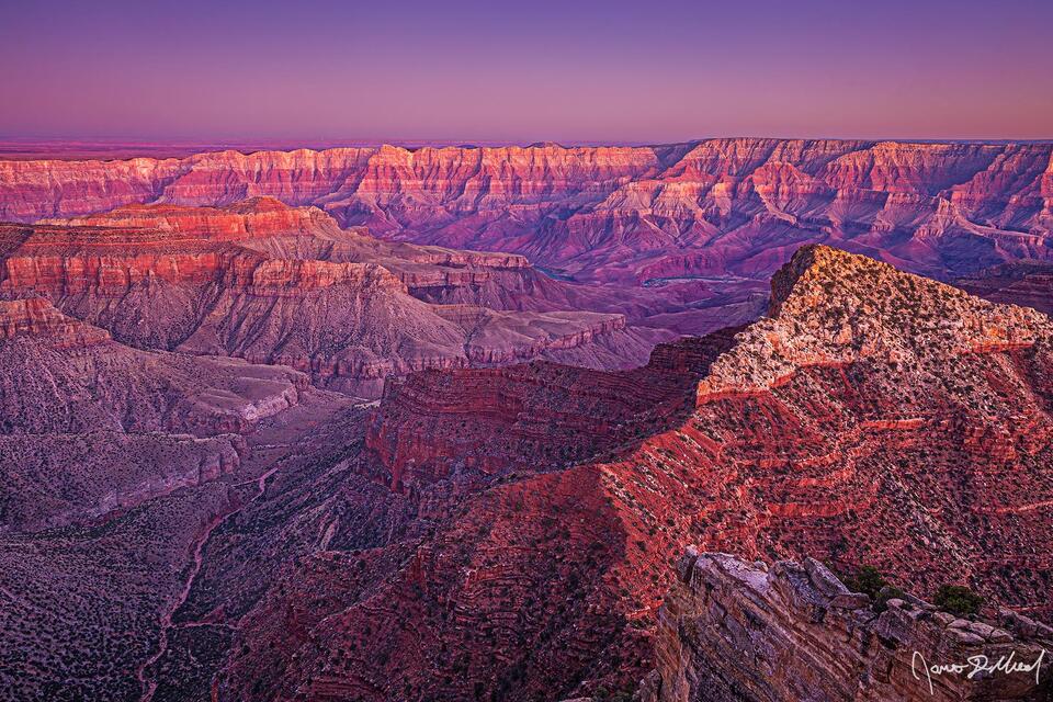 Alpenglow after sunset illuminates the skies over the Grand Canyon, Unkar Creek and the Colorado River with beautiful pastel colors as the day draws to a close.