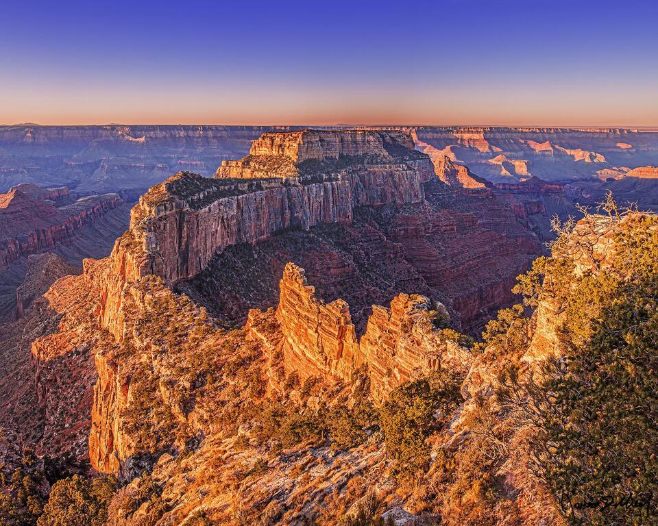 Sunrise casts a warm glow onto Wotan's Throne, Cape Royal and the south rim of the Grand Canyon in the distance as a new day begins.