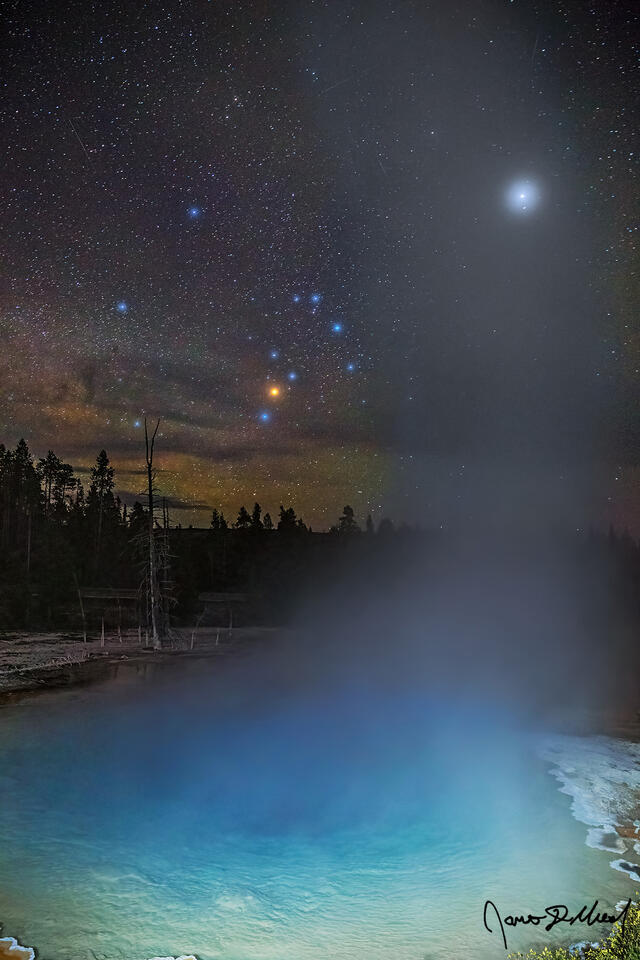 Steam rises from Silex Spring in the Lower Geyser Basin of Yellowstone while Jupiter and Scorpius shine brightly in the night sky as the Milky Way rises.