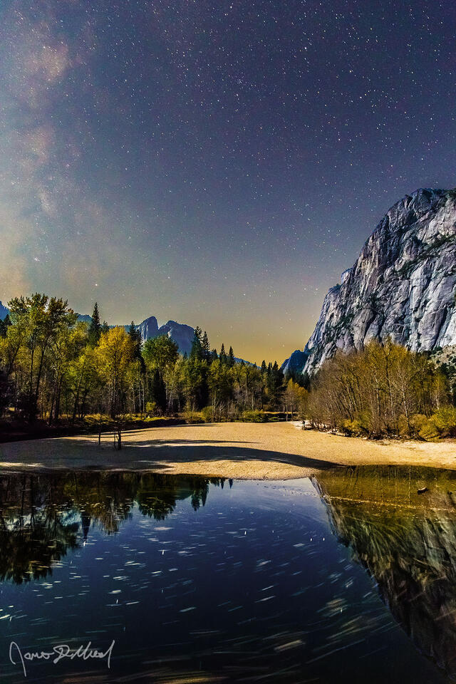 The Milky Way rises into the sky above Lower Brother, Cathedral Rocks, the Merced River and Yosemite Valley as the leaves of the surrounding trees turn gold.
