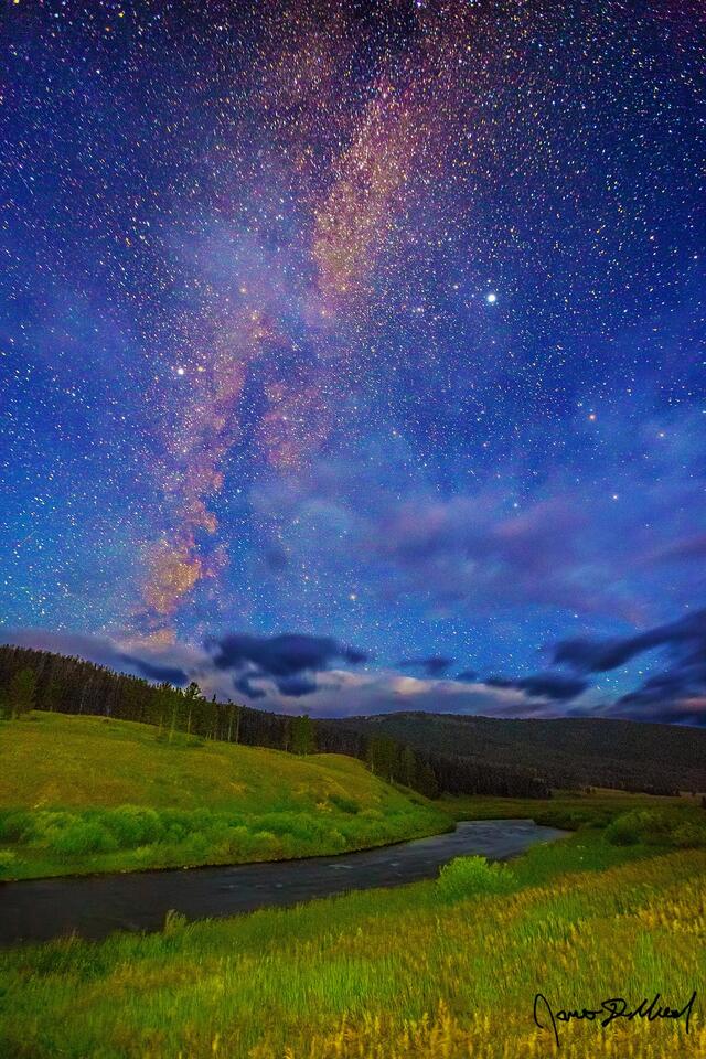 The Milky Way spiral rises high into the sky above the Gallatin River while the greens of the Auroras fade, give way to blue colors as nautical dawn approaches.