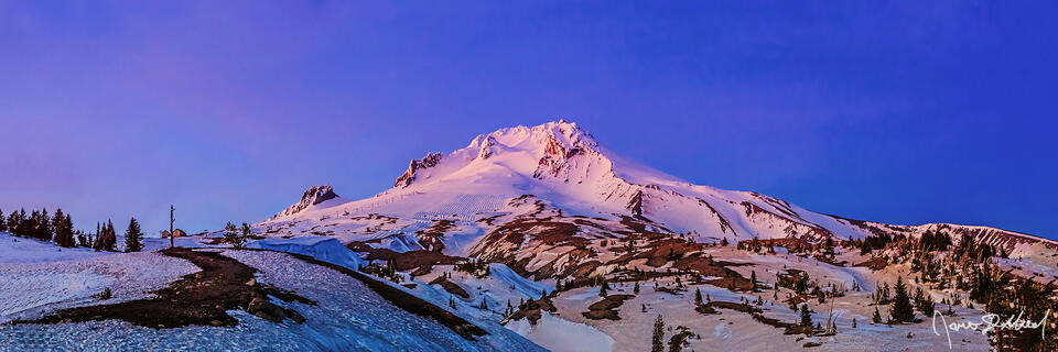 Alpenglow illuminates the snow on Mount Hood at Sunset as soft pastel colors light the clouds in the sky above.