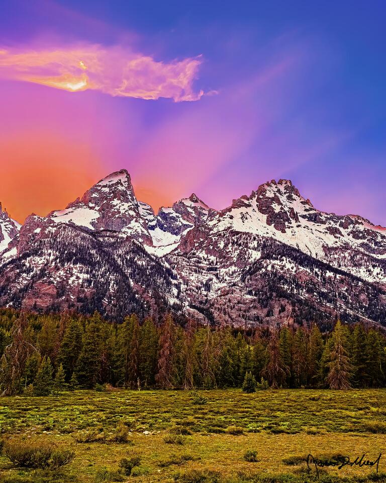 Rays from the setting sun shine up from behind the Cathedral Group, bathing the sky in a glorious mountain light that unveils its majesty for all to behold.