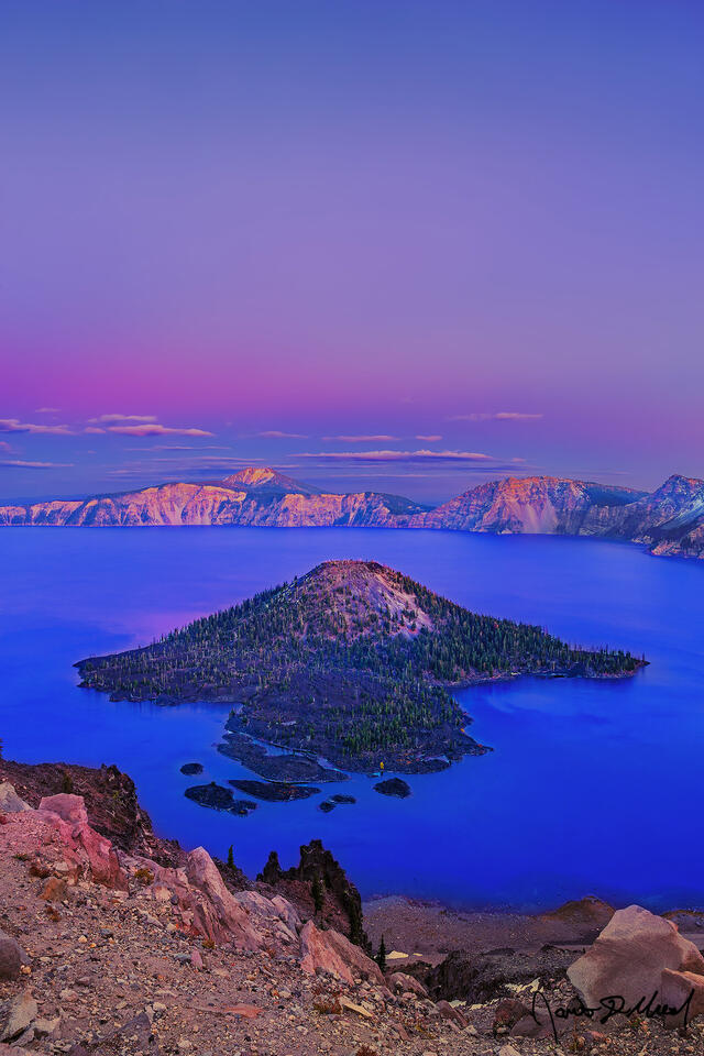 Sunset brings a pastel alpenglow to the skies over Crater Lake and Wizard Island as the day draws to a close.