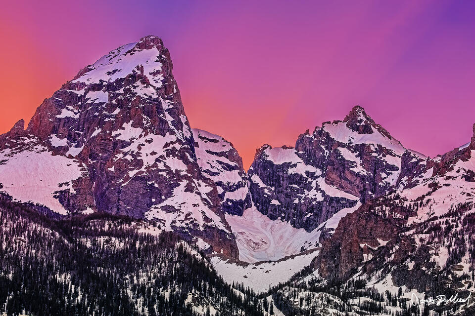 As the sun dips behind the Cathedral Group, radiant beams of light and pastel hues ignite the skies above Grand Teton and Mount Owen.