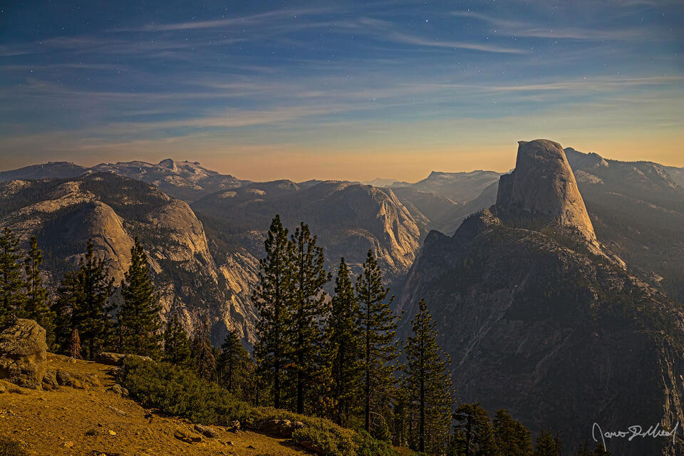Moonlight from the rising moon bathes Half Dome, North Dome, Basket Dome, Mount Watkins and the walls of Tenaya Canyon in a warm glow as stars shine in the nigh
