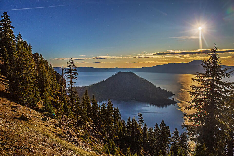 The Hunter’s Moon rises above Wizard Island and the caldera rim, casting its warm glow 6 miles across the waters of Crater Lake as night settles in.