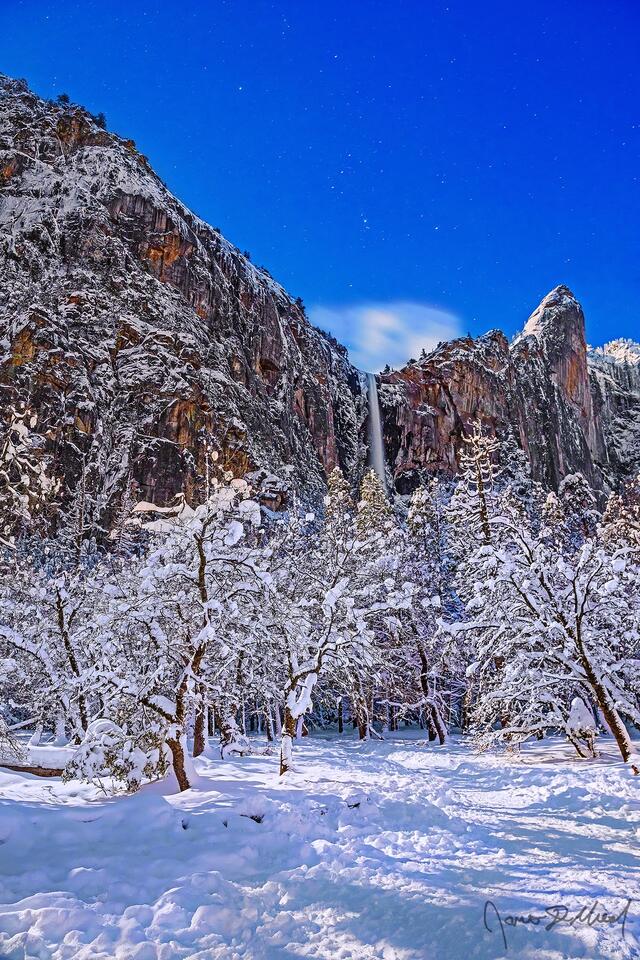 Orion's Belt shines bright in the night sky above a snow covered Bridalveil Meadow in the winter, as Bridalveil Fall tumbles 620 feet over the cliffs