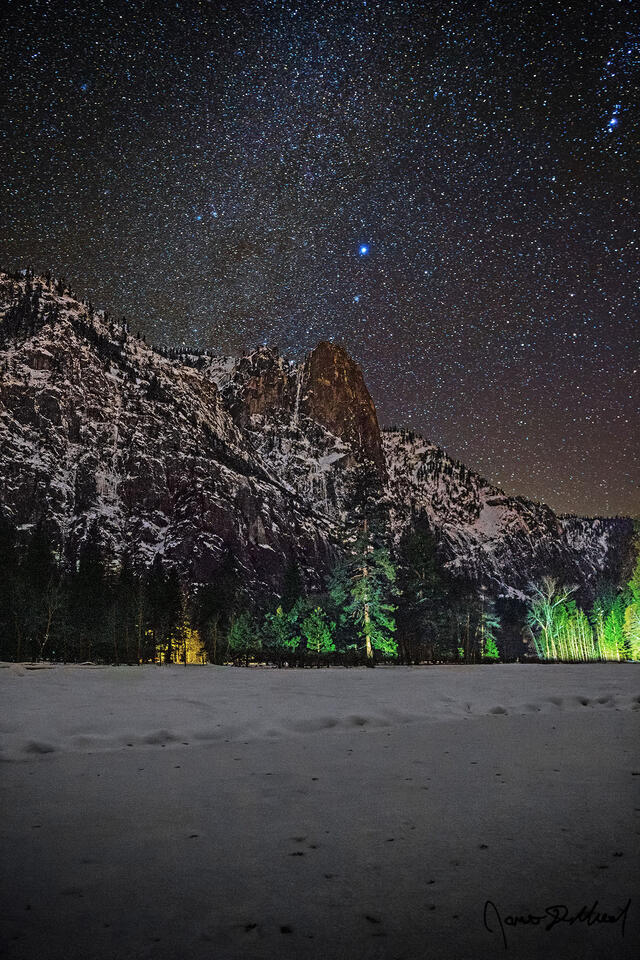 The winter spiral arm of the Milky Way rises over a snow covered Sentinel Meadow in Yosemite Valley as Sentinel Rock rises above towards the night sky.