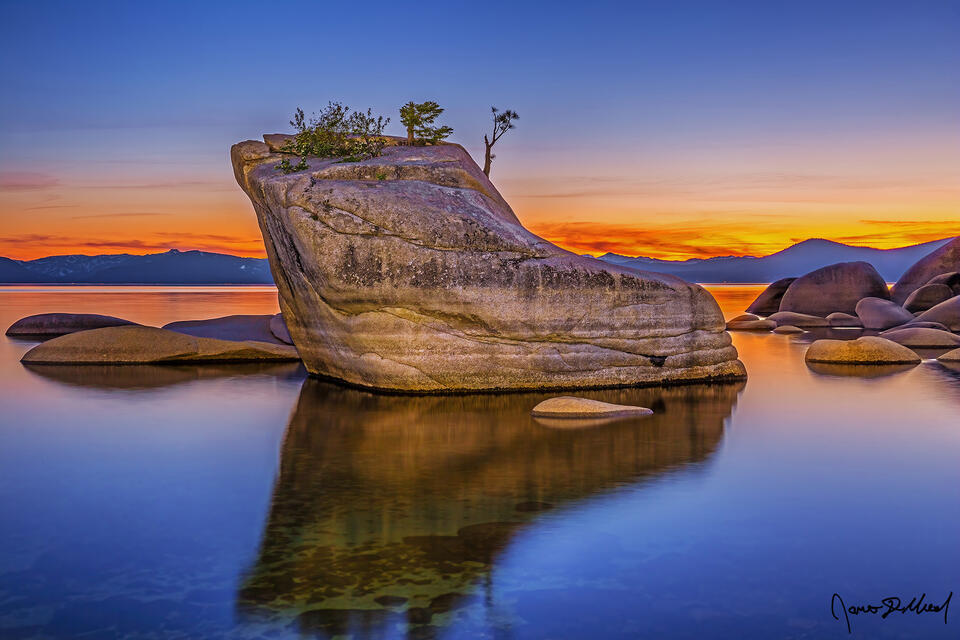 The last light of sunset hangs on in the skies above Bonsai Rock and Lake Tahoe, as the magical scene reflects in the clear, tranquil waters of the lake.