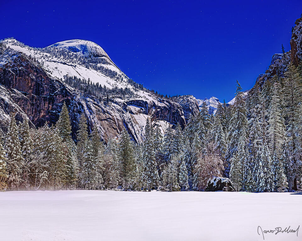 Moonlight illuminates North Dome, the night sky and snow covered Stoneman Meadow as Yosemite Valley transforms into a winter wonderland.