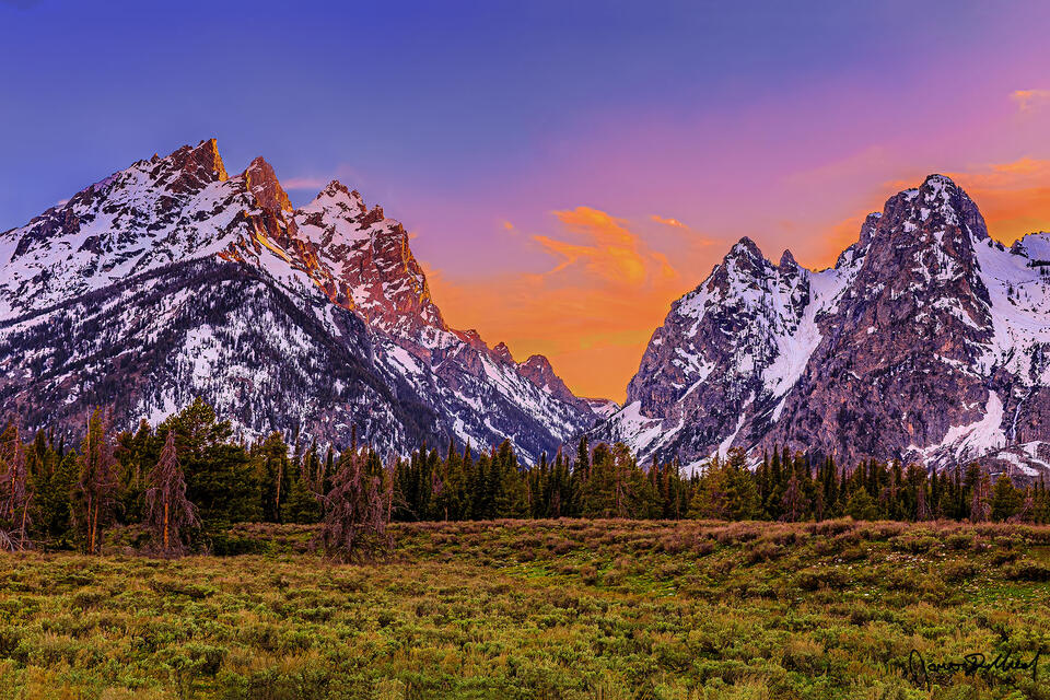 Warm colors of sunset ignite the skies above Cascade Canyon, framed by the Cathedral Group and Mount St John as a pastel glow bathes the skies above.