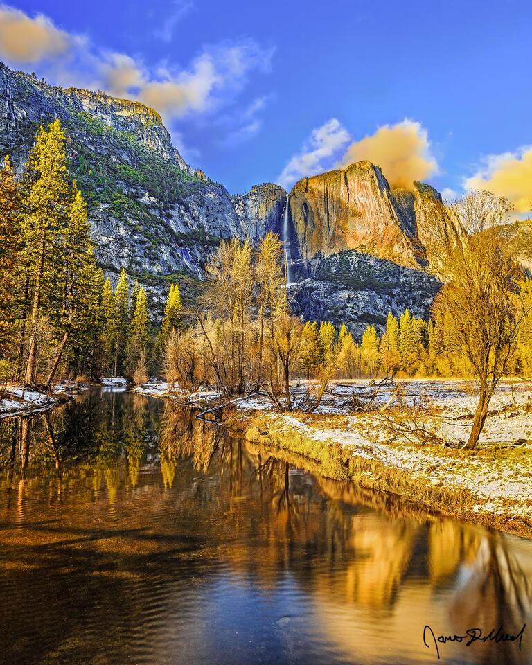 Yosemite Falls plummets 2,425 feet towards Yosemite Valley below while sunset illuminates the granite cliffs, the snow and the valley in a golden hue.