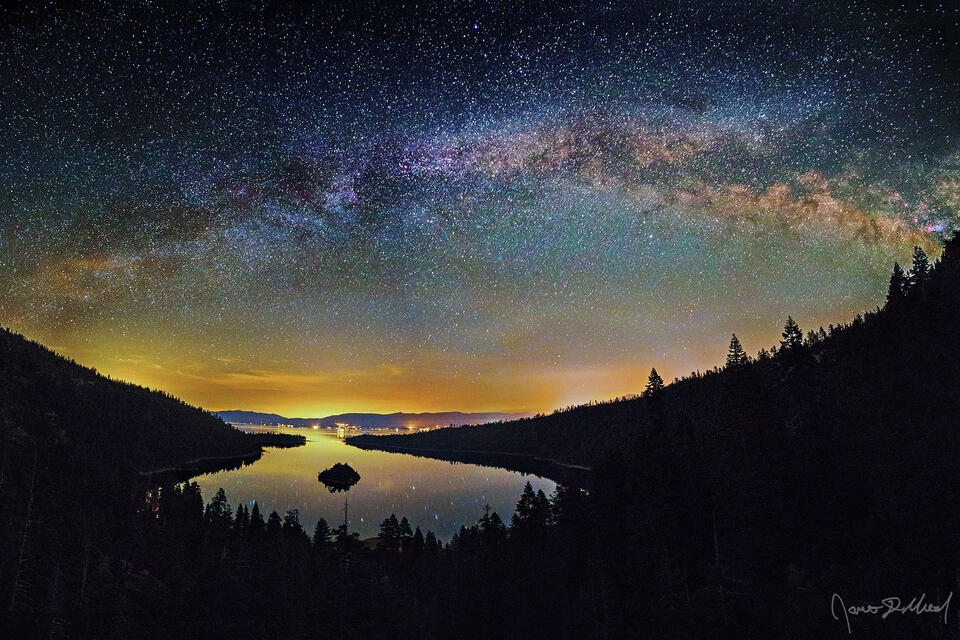 The Milky Way Arch stretches across the night sky over the Sierra Nevada Mountains, the waters of Emerald Bay and Lake Tahoe in California.