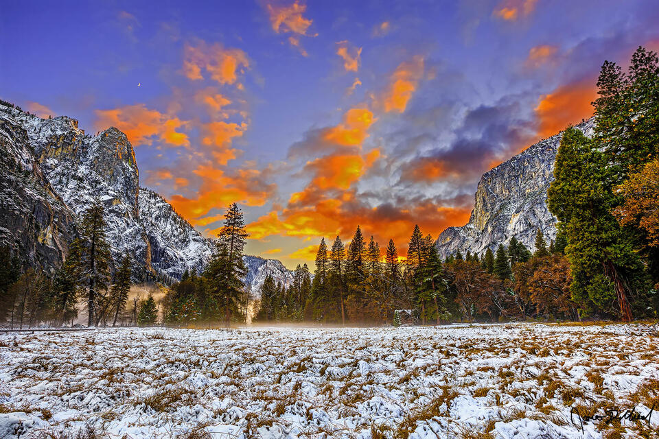 Sunset illuminates the clouds above snow covered Yosemite Valley as mist and fog rise from the valley floor, while a crescent moon sets above Sentinel Rock.