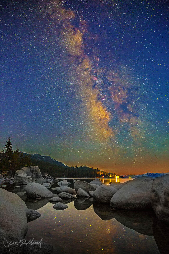 The Milky Way rises and meteors from the Aquariids meteor shower streak across the sky as the Milky Way core and stars reflect in the still waters of Lake Tahoe