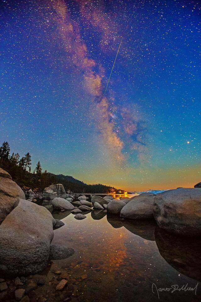 A fast moving meteor from the Aquariids meteor shower streaks across the night sky as the Milky Way reflects in the still waters of Lake Tahoe as Nautical Dawn 