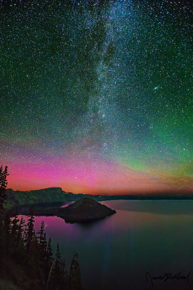 Magentas and greens of the Aurora Borealis light up the skies above Crater Lake and Wizard Island as the spiral arm of the Milky Way rises into the night sky.