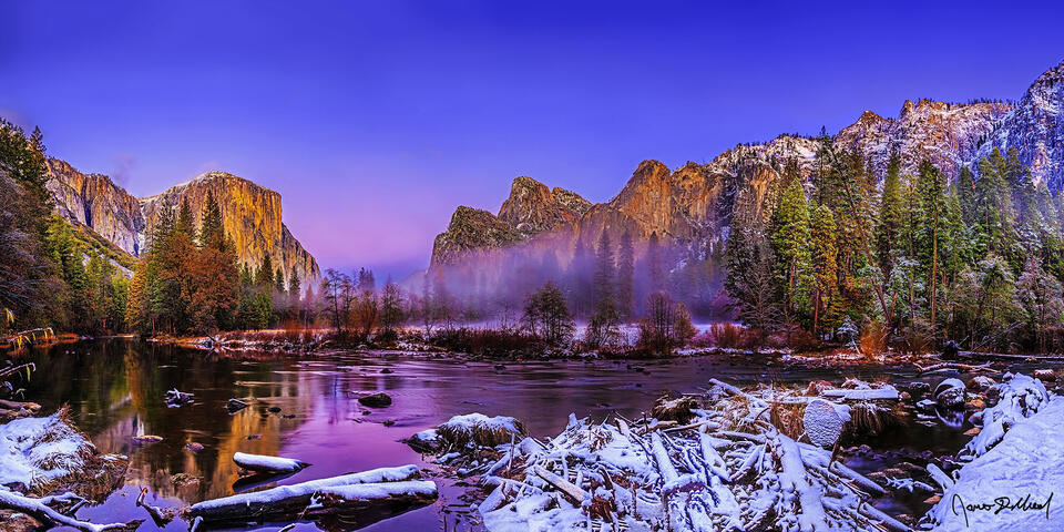 Alpenglow lights the sky above El Capitan and Cathedral Rocks as they rise up from a layer of mist and fog covering Yosemite Valley above the Merced River
