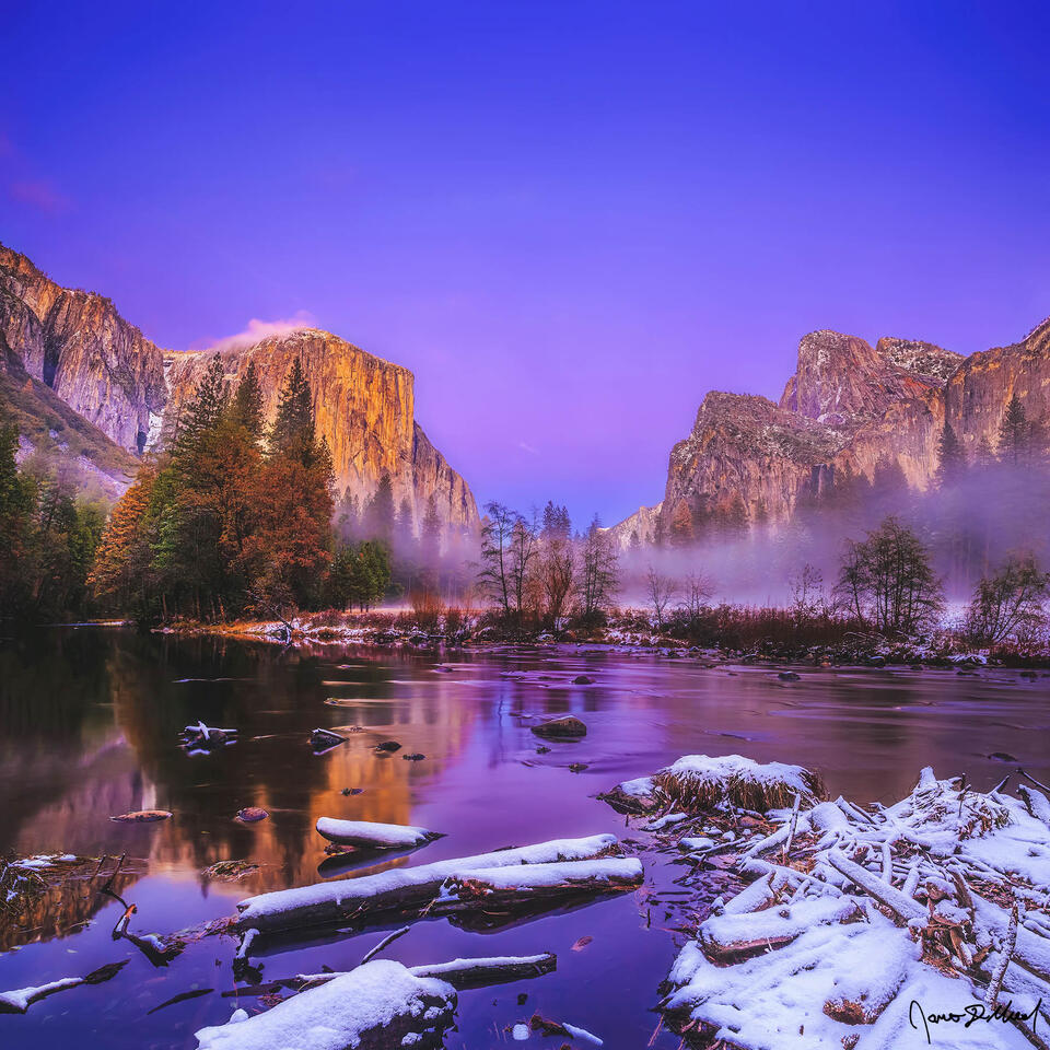 Alpenglow illuminates the skies above El Capitan and Cathedral Rocks as they rise up from a layer of mist and fog covering Yosemite Valley and the Merced River.