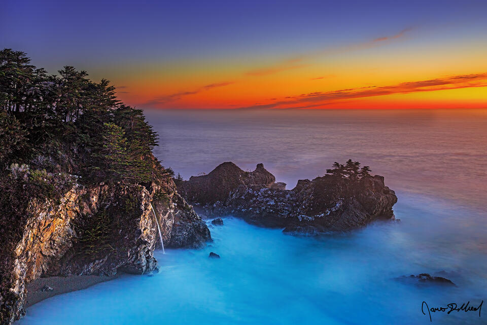 Turquoise water fills McWay Cove as dusk illuminates the skies over McWay Falls and the Pacific Ocean long after sunset.
