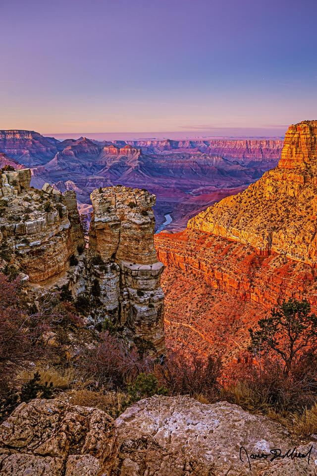 The warm glow of sunset bathes the buttes and temples of the Grand Canyon at sunset as the pastel colors of the Belt of Venus illuminate the skies above.