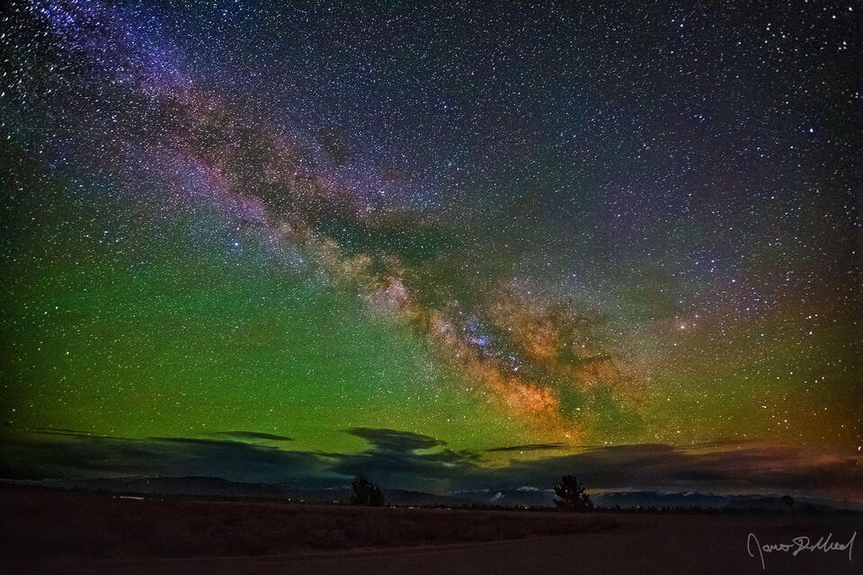 Green airglow fills the night sky as the Milky Way rises over Jackson Hole Valley and the Gros Ventre Range in the distance.