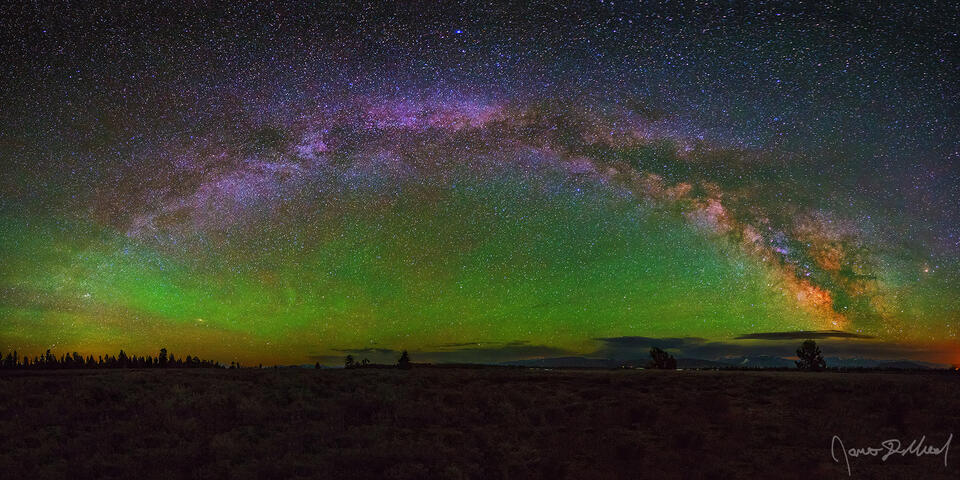 The Milky Way arch stretches across the night sky in Jackson Hole Valley as green airglow illuminates the night skies between the arch and the horizon.