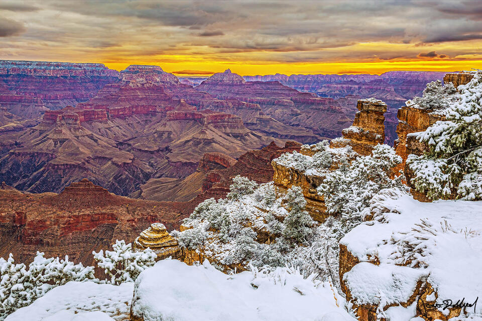 Snow covers the south rim of the Grand Canyon as sunrise illuminates the sky and clouds above Wotans Throne and Vishnu Temple.