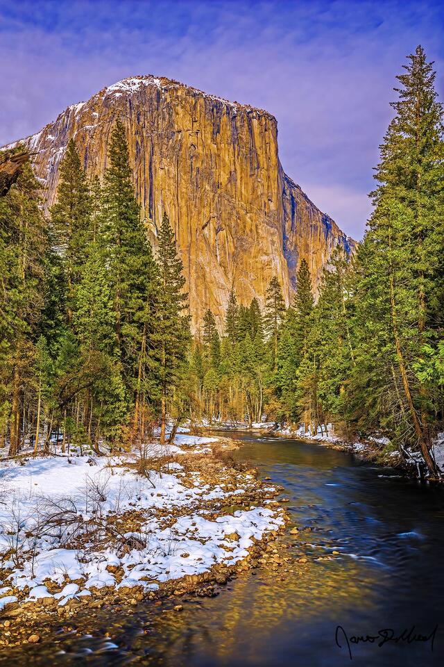El Capitan rises high above the waters of the Merced River as snow blankets Yosemite Valley below.