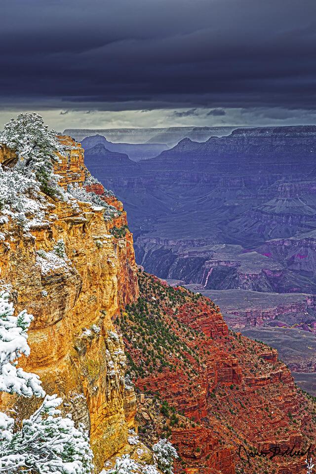 Storm clouds darken the skies above the Grand Canyon as the South Rim and North Rim lay covered in snow.