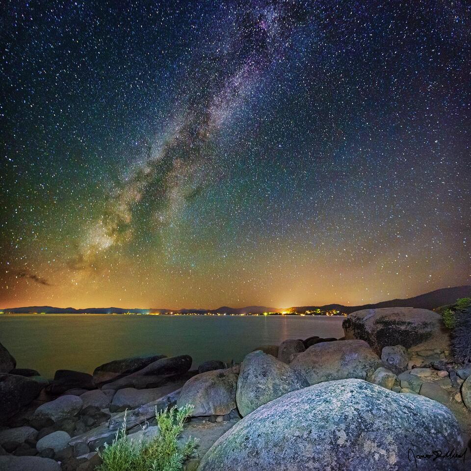 The Milky Way rises high into the night skies above granite boulders along the rocky shoreline of Lake Tahoe.