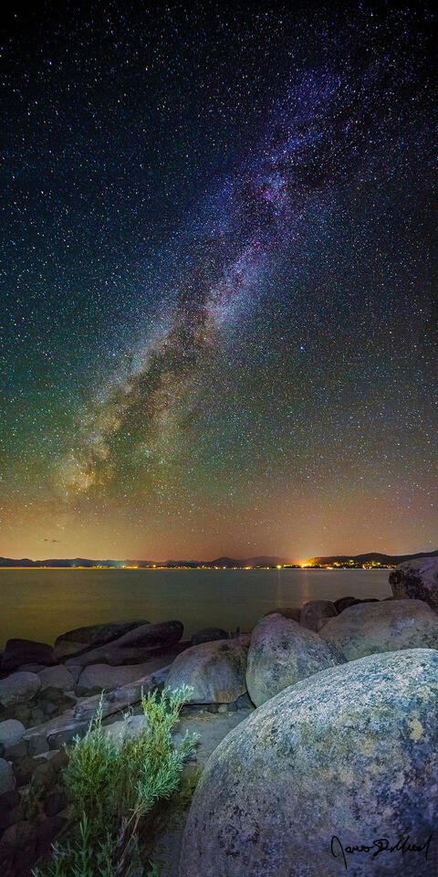 The Milky Way rises high into the night skies above granite boulders along the rocky shoreline of Lake Tahoe.