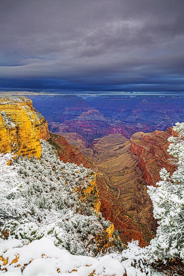 Storm clouds darken the skies above the Grand Canyon as the South Rim and North Rim lay covered in snow.