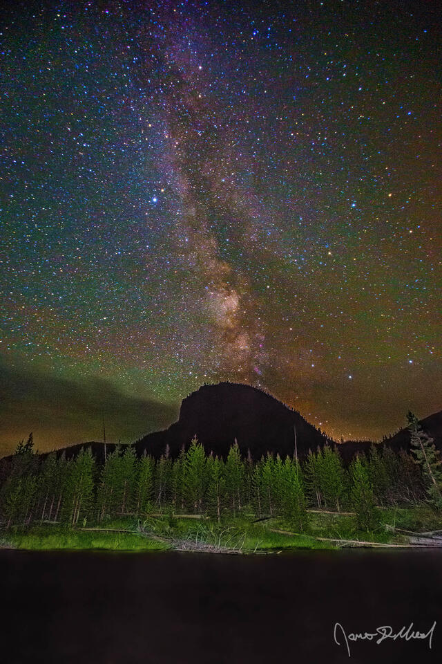 The Milky Way rises high into the skies over Mount Haynes and the Madison River as green airglow illuminates the skies above.