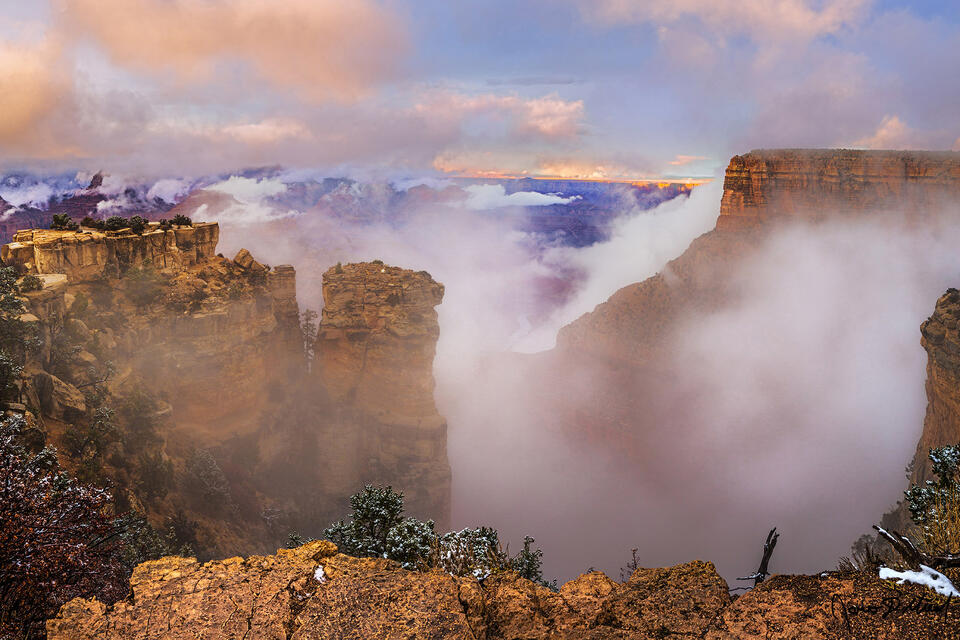 A partial thermal inversion fills the Grand Canyon at Sunset as the Colorado River far below formations rising up through the clouds of the inversion.